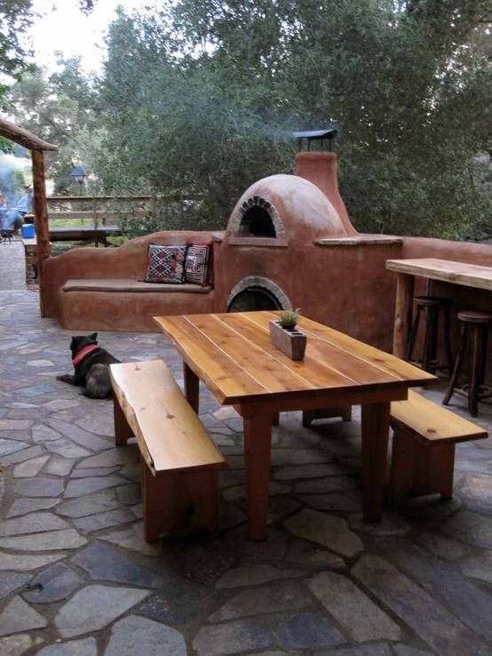 a rustic space with a concrete stove and a wooden dining set plus a stone floor