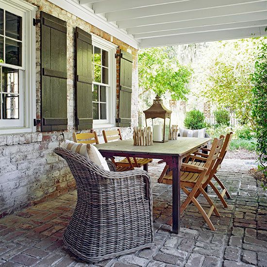 a rustic patio with simple wooden and wicker furniture plus wooden lanterns
