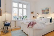 a welcoming Scandinavian bedroom with a white bed, a metal chair, a rug and an artwork