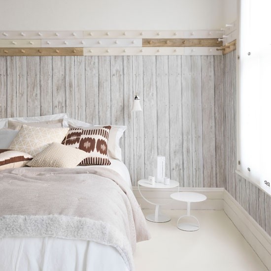 an airy Scandinavian bedroom with whitewashed wood on the walls, a comfy bed, nightstands and hooks on the wall