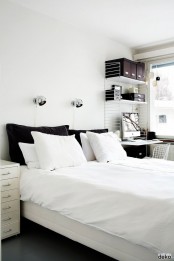 a laconic Nordic bedroom with neutral wooden furniture, a cozy working space in the corner, a wire chair and wall lamps