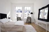 an airy Scandi bedroom with a blakc bed, mirror, chairs with a zebra print and a floor lamp
