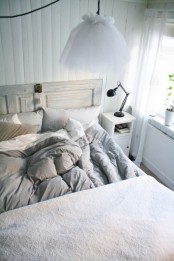 an air-filled Scandinavian bedroom with white walls, a whitewashed wooden bed, white nightstands and pendant lamps
