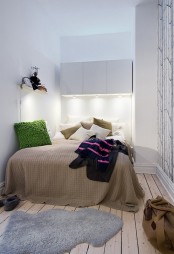 a small Scandinavian bedroom with sleek white surfaces, a wooden floor, a comfy bed and bright bedding