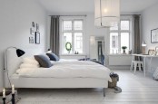 an airy monochromatic bedroom with a pendant lamp, a white upholstered bed, neutral bedding and lamps and lights