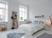 an airy Scandinavian bedroom with white walls and a floor, vintage rustic furniture and lamps and greenery
