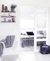 a small Nordic bedroom with a white bed, graphic bedding, skylights and chairs as nightstands