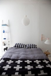 a Scandinavian bedroom with simple minimal furniture, graphic bedding and a pendant lamp