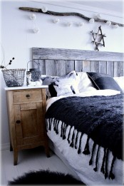 a Nordic bedroom with a weathered wood bed, a rustic wooden nightstand, lights over the bed and baskets