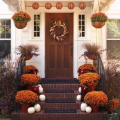 white pumpkins, bold fall blooms in pots, candle lanterns and a garland of paper pumpkins plus a fall wreath of corn and corn husks