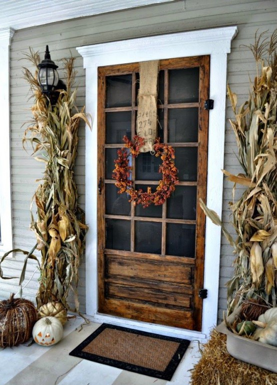 corn husks, vine and natural neutral pumpkins plus a bright pinecone and burlap wreath make up a rustic front front for Thanksgiving
