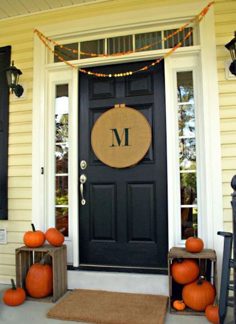 simple Thanksgiving decor with a colorful paper garland, a burlap monogram sign and crates with natural orange pumpkins