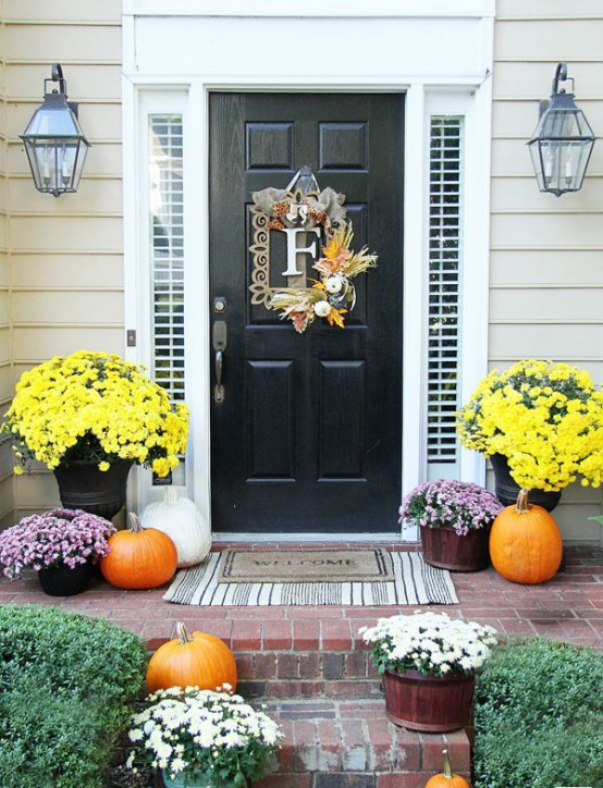 a whimsy framed F wreath with greenery and pumpkins, bright fall blooms in pots and orange and white pumpkins
