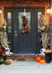corn husks and sunflowers, orange and green pumpkins and a decoration made of faux pumpkins and foliage for a Thanksgiving front door
