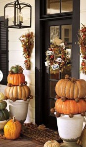 stacks of pumpkins, fall leaf arrangements and wreaths with lights create a cozy ambience in the porch