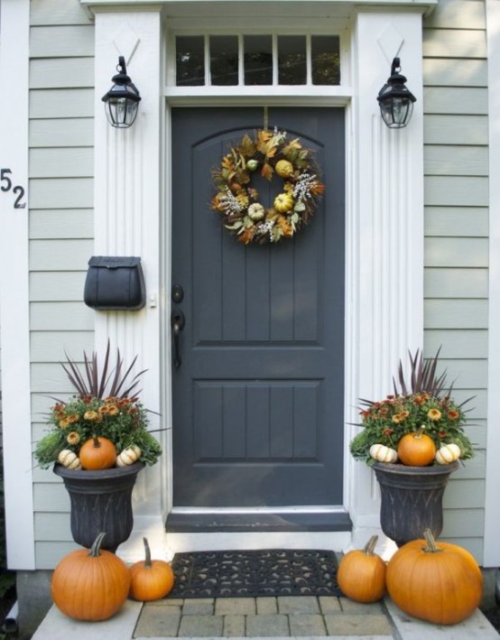 greenery and bloom arrangements with pumpkins, feathers, pumpkins on the floor and a fall wreath of feathers, foliage and pumpkins on the door