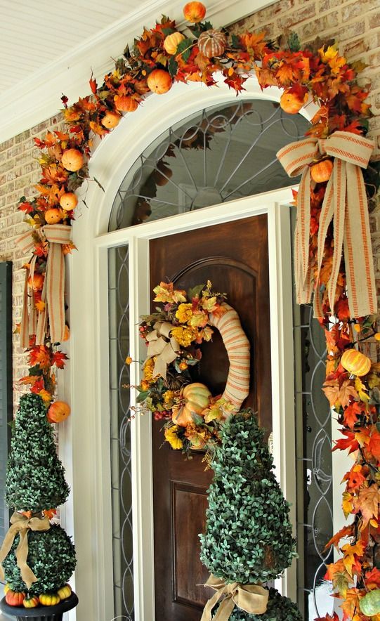 a chic and preppy Thanksgiving front door with faux pumpkins and leaves, burlap bows and a lush wreath of leaves, pumpkins and berries