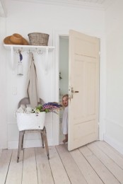 a vintage entryway with white walls, doors and a whitewashed floor that brings a relaxed touch to the space