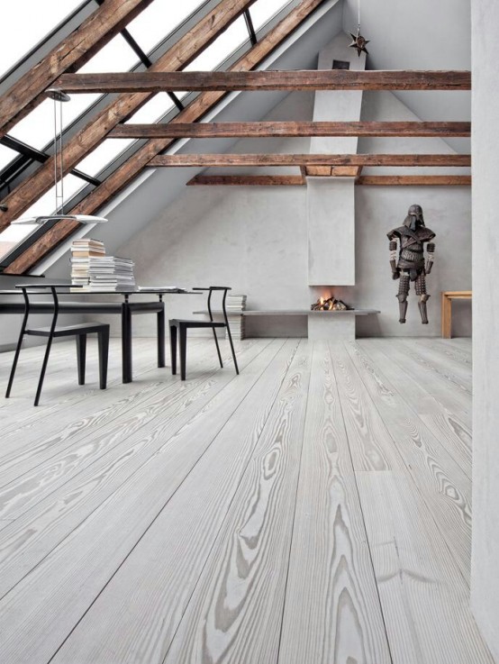 an eclectic space with concrete walls, wooden beams, a grey whitewashed floor and dark contrasting furniture