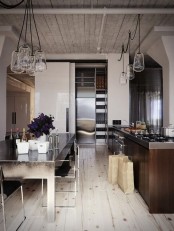 a contrasting kitchen with a whitewashed floor and ceiling and dark furniture plus pendant glass lamps