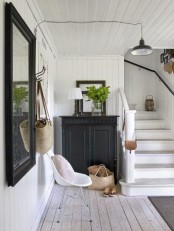 a black and white farmhouse entryway with a whitewashed floor and black furniture and lighting looks lovely
