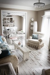 a shabby chic living room with whitewashed wooden floors, white vintage furniture and pastel textiles