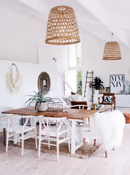 a boho beach dining space in neutrals, with a dining table and white chairs, wicker lampshades and artwork and pampas grass