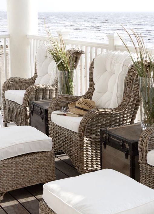 a coastal porch with wicker chairs and some poufs with white upholstery are classics and perfection for coastal and beach spaces