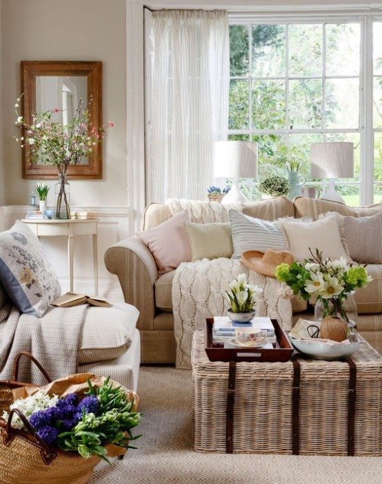 a neutral farmhouse living room with neutral seating furniture, a white side table and artwork, a wicker chest for storage and as a coffee table