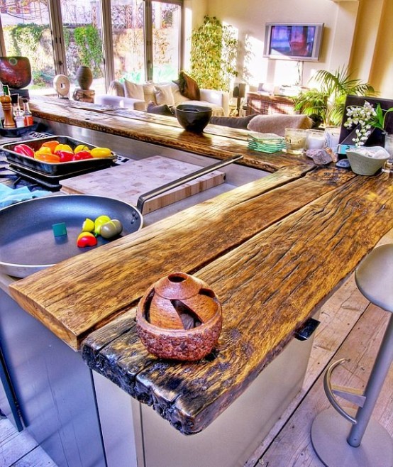 a rough and weathered wood slab kitchen countertop is a very cool idea to add a rustic touch to the space