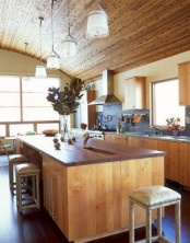 a chalet kitchen clad with wood, with stone countertops and a wooden kitchen island with rich stained countertops that contrast the space and makes it interesting