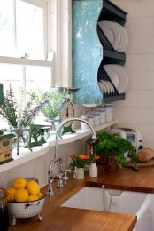 a white kitchen spruced up with rich stained wooden countertops and a blue shabby chic open shelving unit