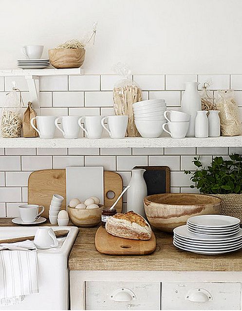 a white Nordic kitchen with light stained wooden countertops, wooden bowls and baskets for a cozy feel