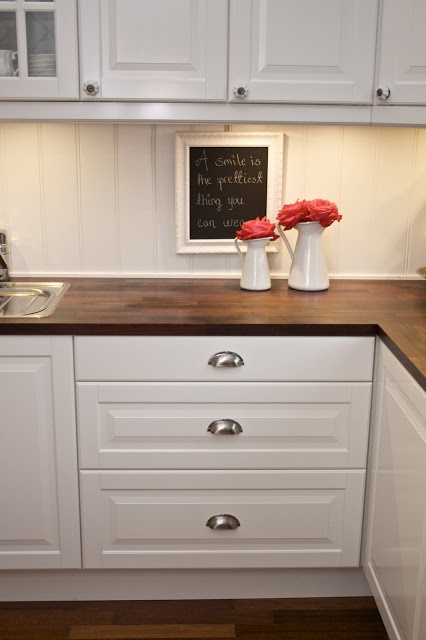 dark stained wooden kitchen countertops contrast the white cabinets and add a dramatic touch to the space