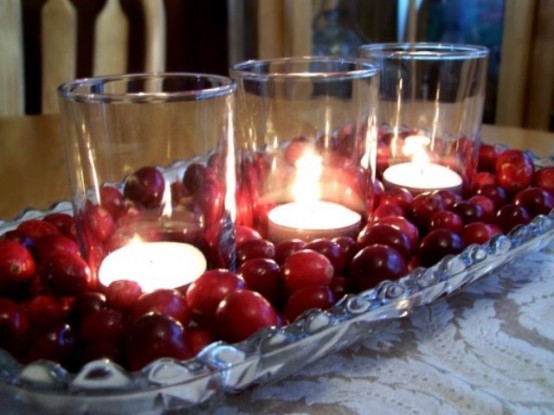 a Christmas centerpiece of a silver tray, cranberries and glasses with candles is a very cozy and lovely idea, perfect for a naturally decorated space