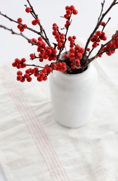 a white bottle-shaped vase with holly berries is a lovely decor idea for the holidays, and it's very easy to compose