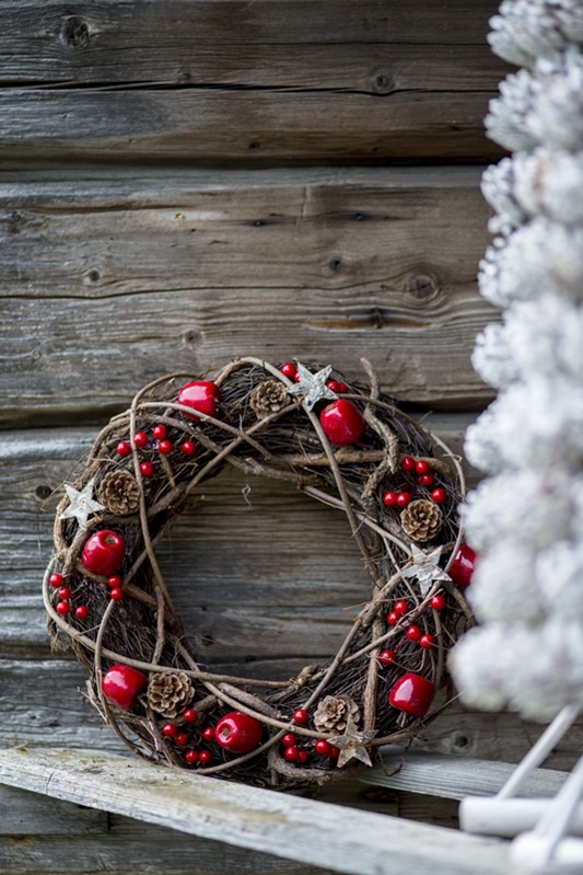 a vine Christmas wreath with branches, pinecones, cranberries, apples and wooden stars is a lovely and bold decoration for Christmas