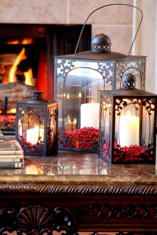 black ornated candle lanterns filled with cranberries inside and with pillar candles are amazing for rocking them on a Christmas table or console