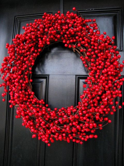 a gorgeous Christmas wreaht fo vine,w ith red cranberries all over is a lovely decor idea for a holiday porch