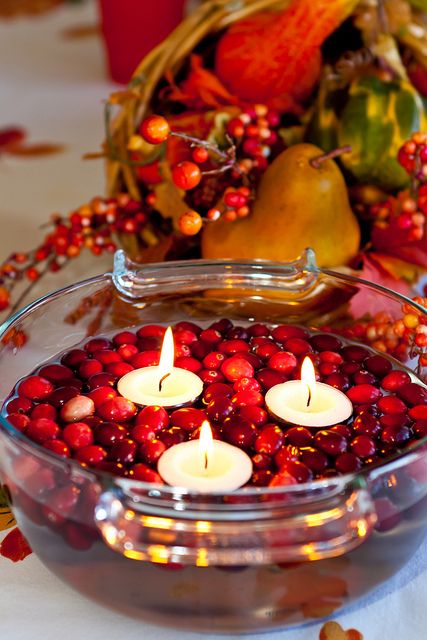 a glass bowl with cranberries and floating candles is a simple and cool Christmas decoration or centerpiece
