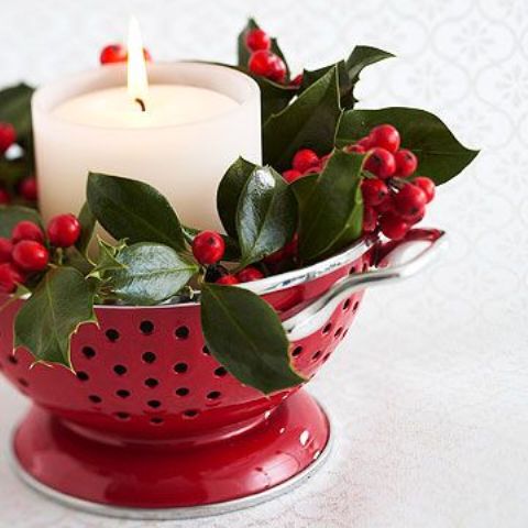 a red colander with greenery, cranberries and a pillar candle is a lovely and easy decor idea for a Christmas kitchen