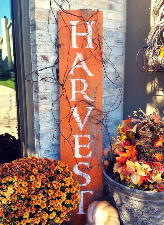 a bright orange fall sign and fall blooms and berries arranged in buckets and bathtubs