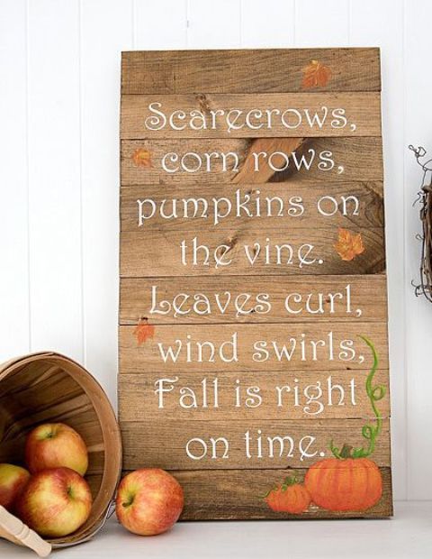 a beautiful wood plank sign with pumpkins and fall leaves plus a wooden basket with apples next to it