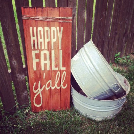 a bright orange fall sign and some buckets next to it to create a relaxed rustic fall feel