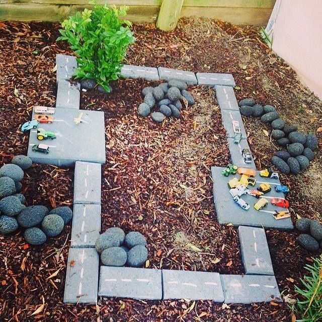 a small playground with pebbles, stepping stones, colorful little toy cars is a cool and cozy nook to play in