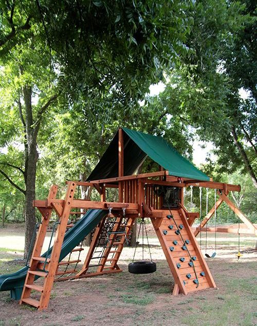 a cool outdoor sports ground with climbing walls, ladders, a tyre swing and a small tree house up there