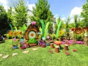a colorful fairy playground with bright blooms, tree stumps, painted stones and other stuff for fun