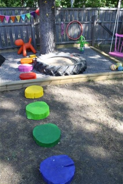 a colorful playground with bright buntings, colorful tree stumps as stepping stones, a small sand box of a giant tyre