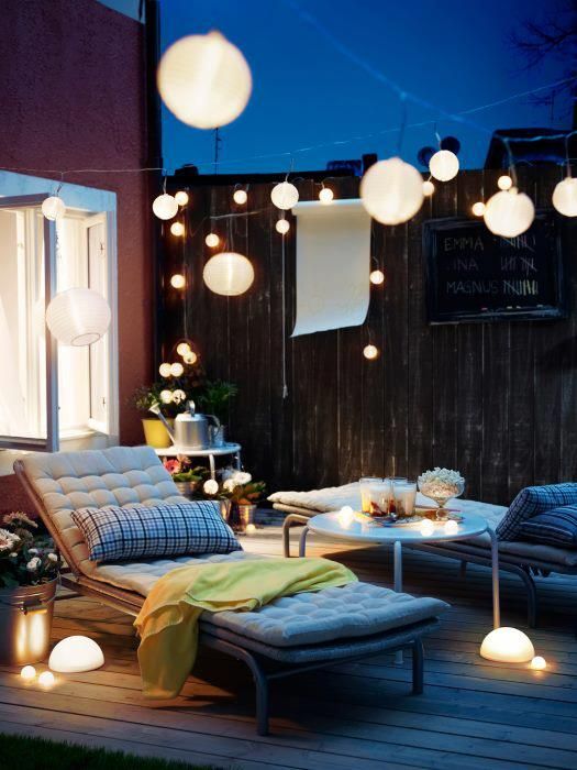 a pretty terrace with neutral loungers, with a coffee table and pendant lamps, string lights and lights on the floor is a great space to enjoy