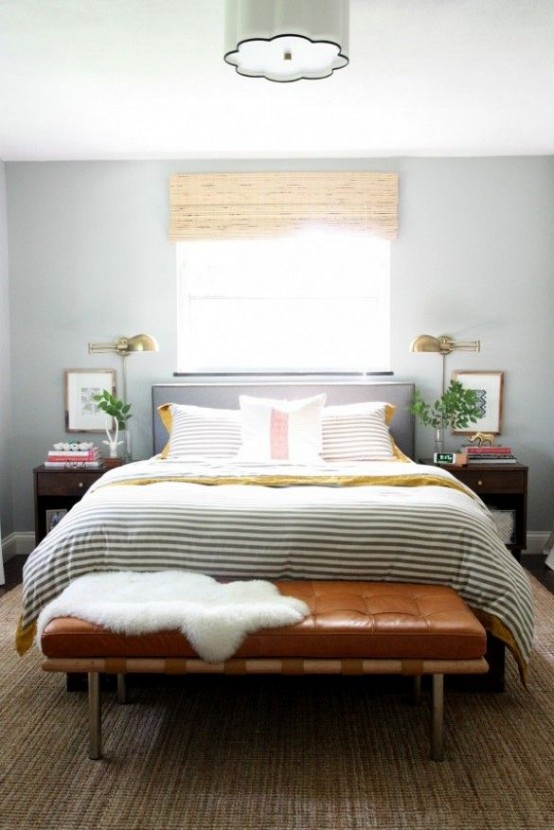 a cozy light grey mid-century modern bedroom with a bed, nightstands, a leather bench and striped bedding is super cool